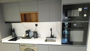 Eine moderne Küche mit Einbauwaschmaschine, Kaffeemaschine und Mikrowelle.