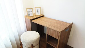 Ein kompakter Holztisch mit integriertem Regal, ein runder Hocker und zwei gerahmte Bilder an der Wand.
