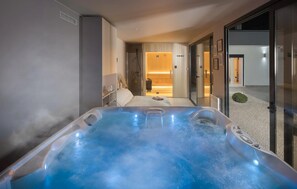 Ein modernes Hotelzimmer mit einer großen Badewanne, einem Bett und einer begehbaren Dusche.