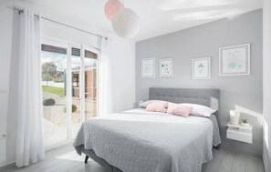 Ein Schlafzimmer mit einem Bett, einem Nachttisch, einem Fenster mit Vorhängen und gerahmten Bildern an der Wand.