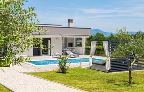 Ein modernes Haus mit Swimmingpool, Sitzgelegenheiten im Freien und Blick auf die Berge.