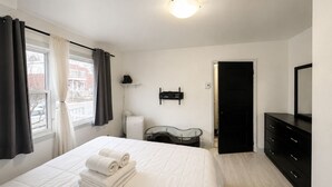 A hotel room with a bed, a dresser, a mirror, and a radiator. - Modern 3BR Home Near Montreal | Free Parking (Longueuil)