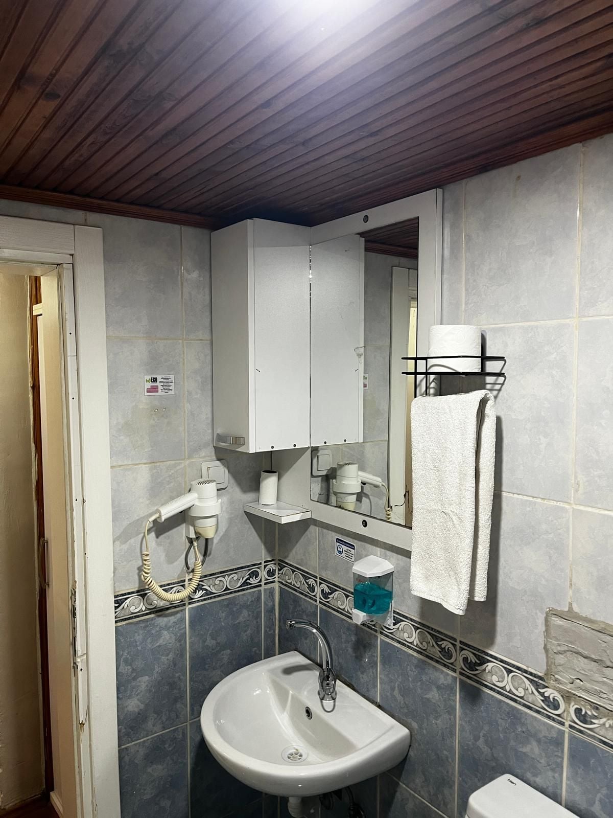 A bathroom with a white sink, a mirror, a towel rack, and a toilet.