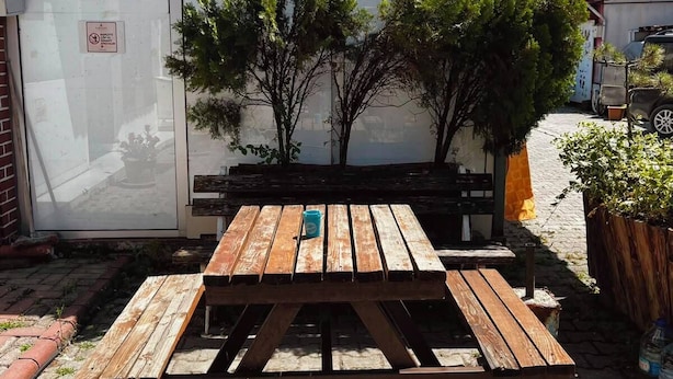 A wooden table and benches outside a building with a window.