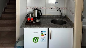 A compact kitchen with white cabinets, a built-in sink, and a refrigerator with an ENERGY STAR rating sticker.