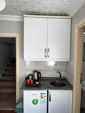 Cocina compacta con gabinetes blancos, un lavamanos integrado y un refrigerador con etiqueta de eficiencia energética ENERGY STAR.