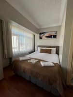 Habitación de hotel con una cama grande, un cuadro en la pared y una ventana con cortinas.