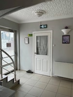 Interior limpo e moderno, com uma porta branca, uma escada e um radiador.