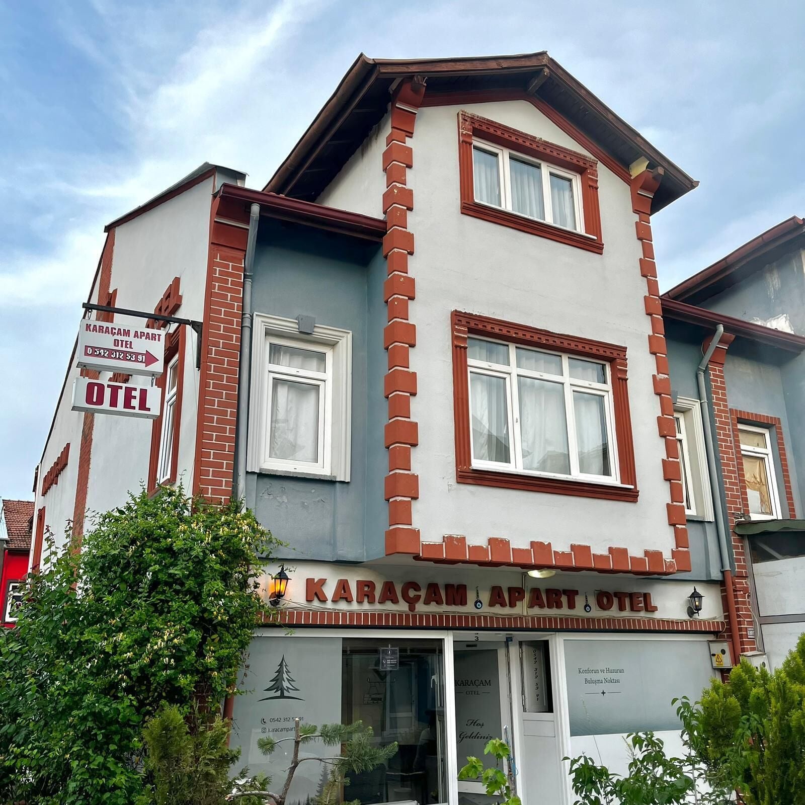 A building with a sign for 'Karacam Apart Hotel' and a contact number.