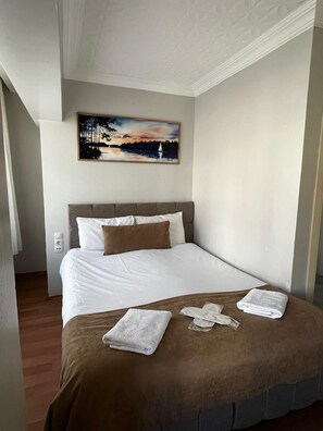 Habitación de hotel con cama, un cuadro sobre ella y piso de madera.
