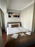 Quarto de hotel com uma cama, um quadro acima e piso de madeira.