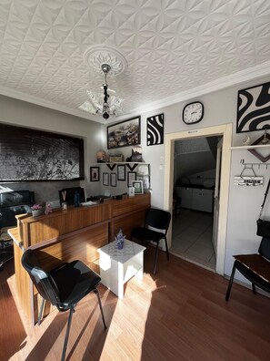 A modern living room with a wooden reception desk, black chairs, a white coffee table, and a ceiling fan. - Karaçam Apart Otel (Kastamonu)