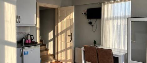 A compact room with a kitchenette, a dining area, and a bed with towels.