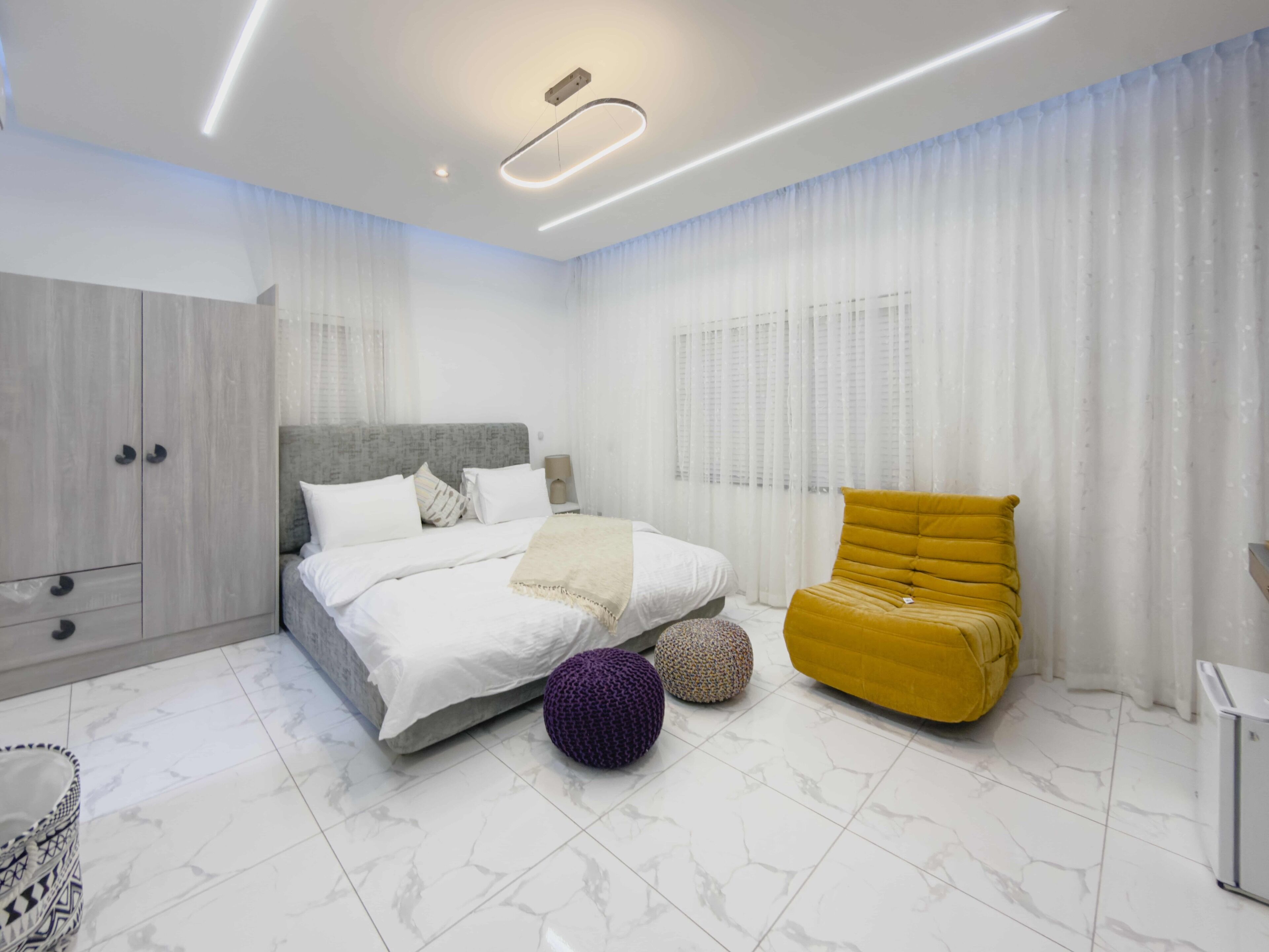 A modern bedroom with a bed, a yellow armchair, and a wardrobe.