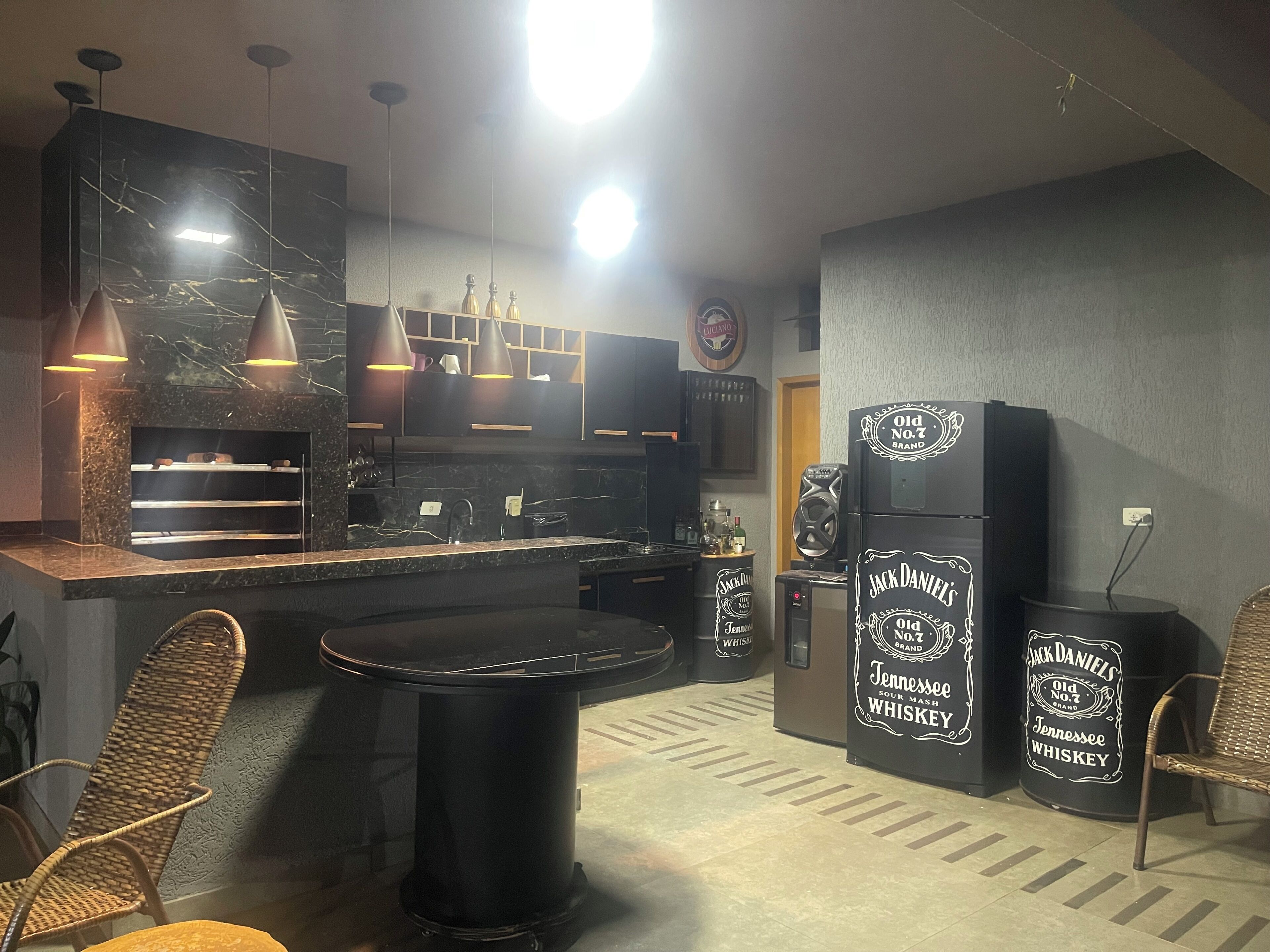 Uma cozinha moderna com armários escuros, bancada de mármore, iluminação pendente e uma ilha central.