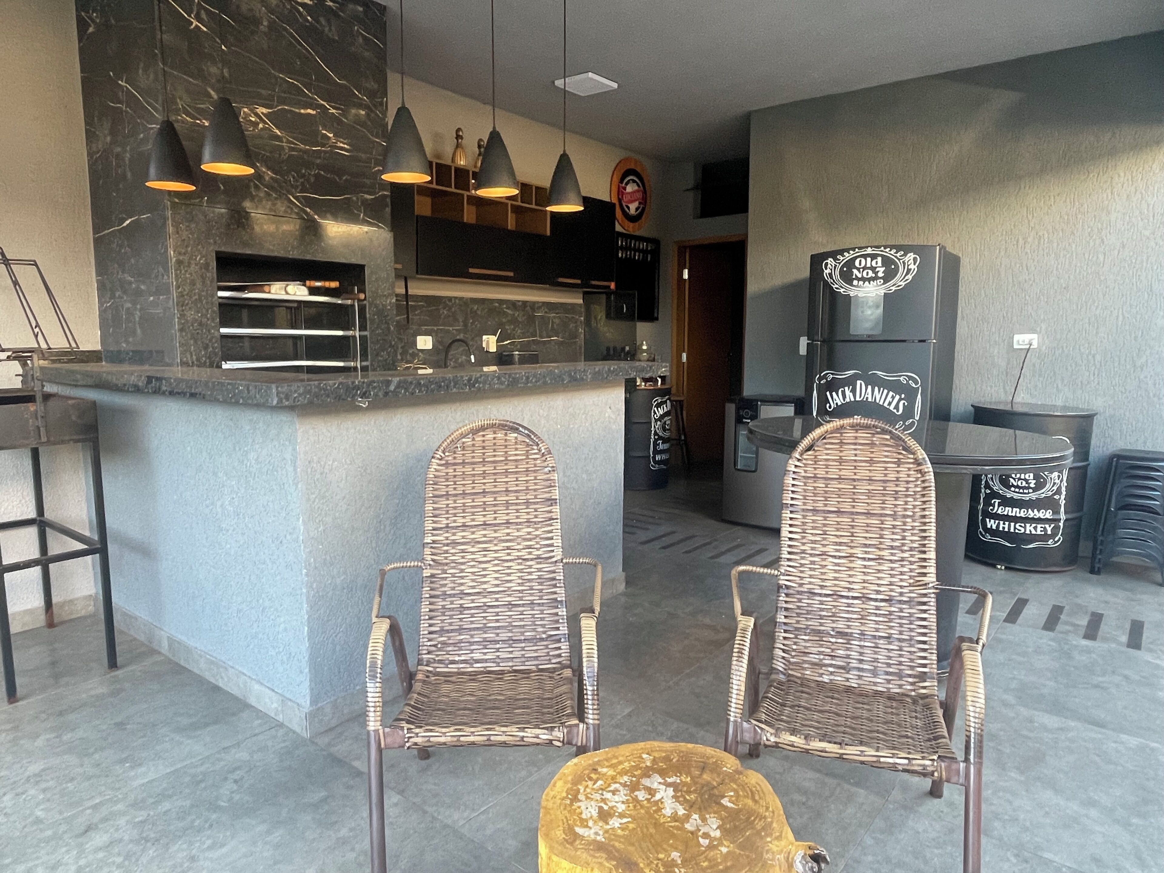 Eine Bar mit einer Theke, zwei Korbstühlen und einem mit 'Jack Daniel's' beschrifteten Kühlschrank.