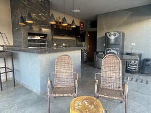 A bar area with a counter, two wicker chairs, and a refrigerator labeled 'Jack Daniel's'.