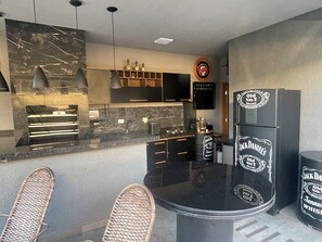 A modern kitchen with a black countertop, built-in appliances, and a dining area with wicker chairs.