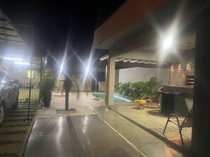 An outdoor patio area with a pool, seating, and a car parked nearby.