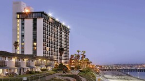 Um hotel à beira-mar com um edifício amplo, uma praia e um cais ao fundo.