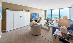 Un saló modern amb un televisor de pantalla plana gran, un sofà, una taula baixa i vista a l'oceà.