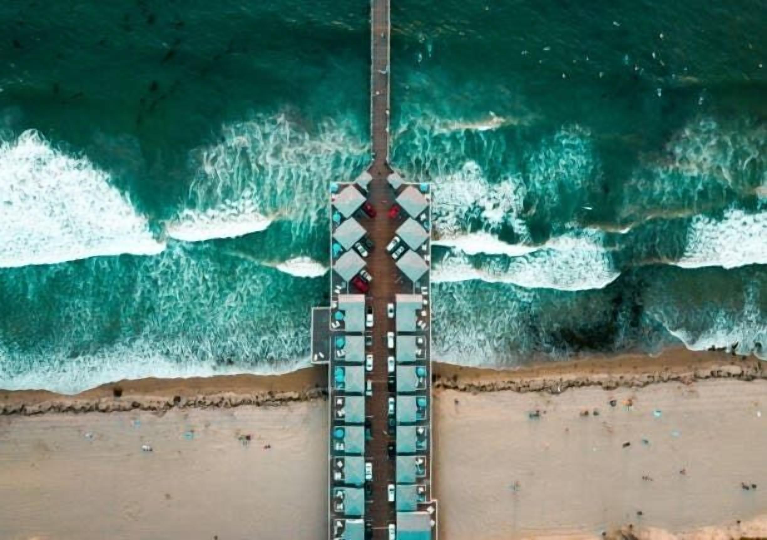 A pier extending into the sea with rows of cabins.