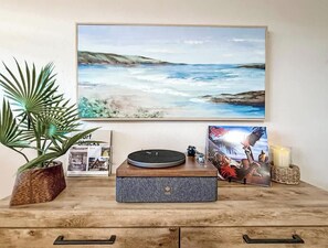 A wooden table with a turntable, a framed picture of a beach, a potted plant, and a candle. - The Palm & Sea! (Ocean Views!) (San Diego)