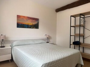 A bedroom with a bed, two bedside tables, a wall-mounted shelf, and a painting. - La Graciosa Apartment 2033 (San Miguel de Meruelo)
