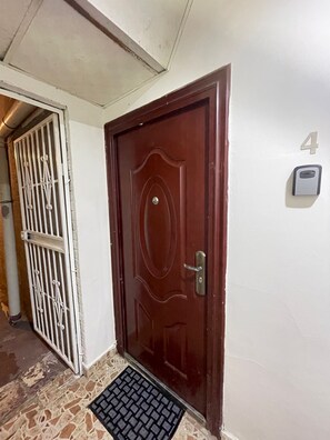 A brown door with a number '4' sign above it, a keypad lock, and a metal gate to the left.