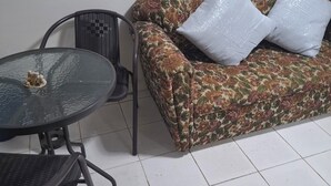 A room with a floral sofa, two white pillows, a glass-top table, and a black chair. - Private room in Panama City, near the airport (Panama)