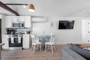 A modern kitchen with white cabinets, a microwave, stove, and a dining area with a round table and white chairs. - July Deals - Pet Friendly and Hot tub! Cottage (Indian Rocks Beach)