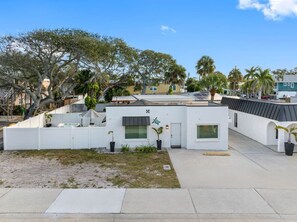A modern house with a white exterior, a small front yard, and a paved driveway. - July Deals - Pet Friendly and Hot tub! Cottage (Indian Rocks Beach)