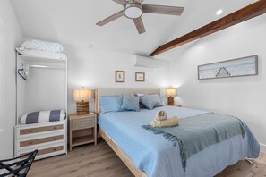 Een slaapkamer met een bed, nachtkastjes, een kledingkast, een plafondventilator en een lijst met een afbeelding aan de muur.