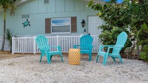 Un bâtiment portant le numéro 205, avec des places assises à l’extérieur, comprenant des chaises et une table, et une clôture blanche.