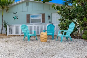 A building with the number 205, outdoor seating with chairs and a table, and a white fence. - July Deals - Pet Friendly & Hot Tub! Suite A (Indian Rocks Beach)