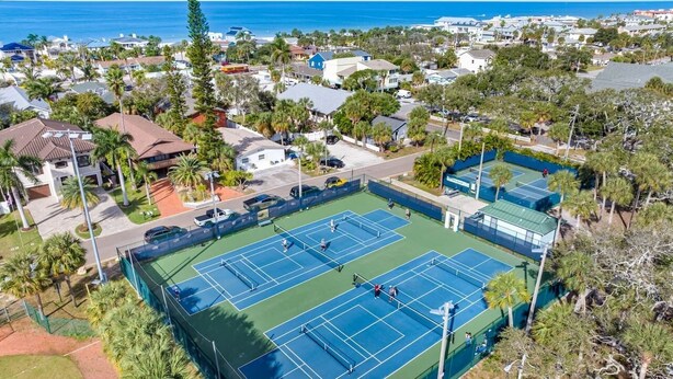 Un court de tennis entouré d’immeubles résidentiels et de palmiers.