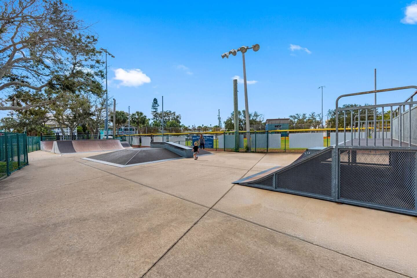 An outdoor skate park with ramps and a fenced area.