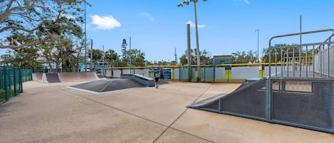 Una pista de skate al aire libre con rampas y un área cercada.