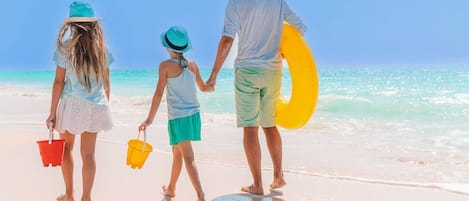 A family walking on a beach with a clear sky.
