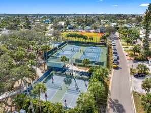 A tennis court complex with multiple courts, surrounded by palm trees and residential buildings. - Sept Deals - Pet Friendly and Hot tub! Suite B (Indian Rocks Beach)