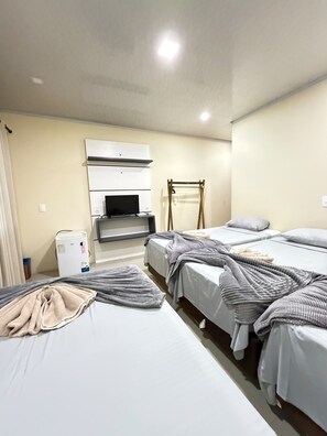 Ett hotellrum med två sängar, en TV, en värmare och ett träställ.