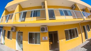 Un edificio amarillo con varias ventanas, un balcón y un letrero de prohibido fumar.