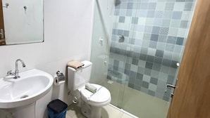 Un baño con lavamanos, inodoro y ducha con mampara de vidrio.