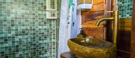A bathroom with mosaic tile walls, a wooden sink, and a white shower curtain.