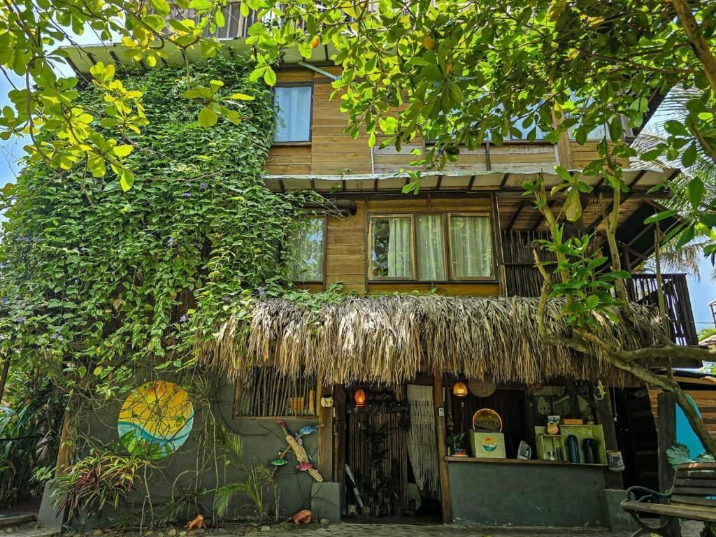 A house with a thatched roof, surrounded by lush greenery and a mural.