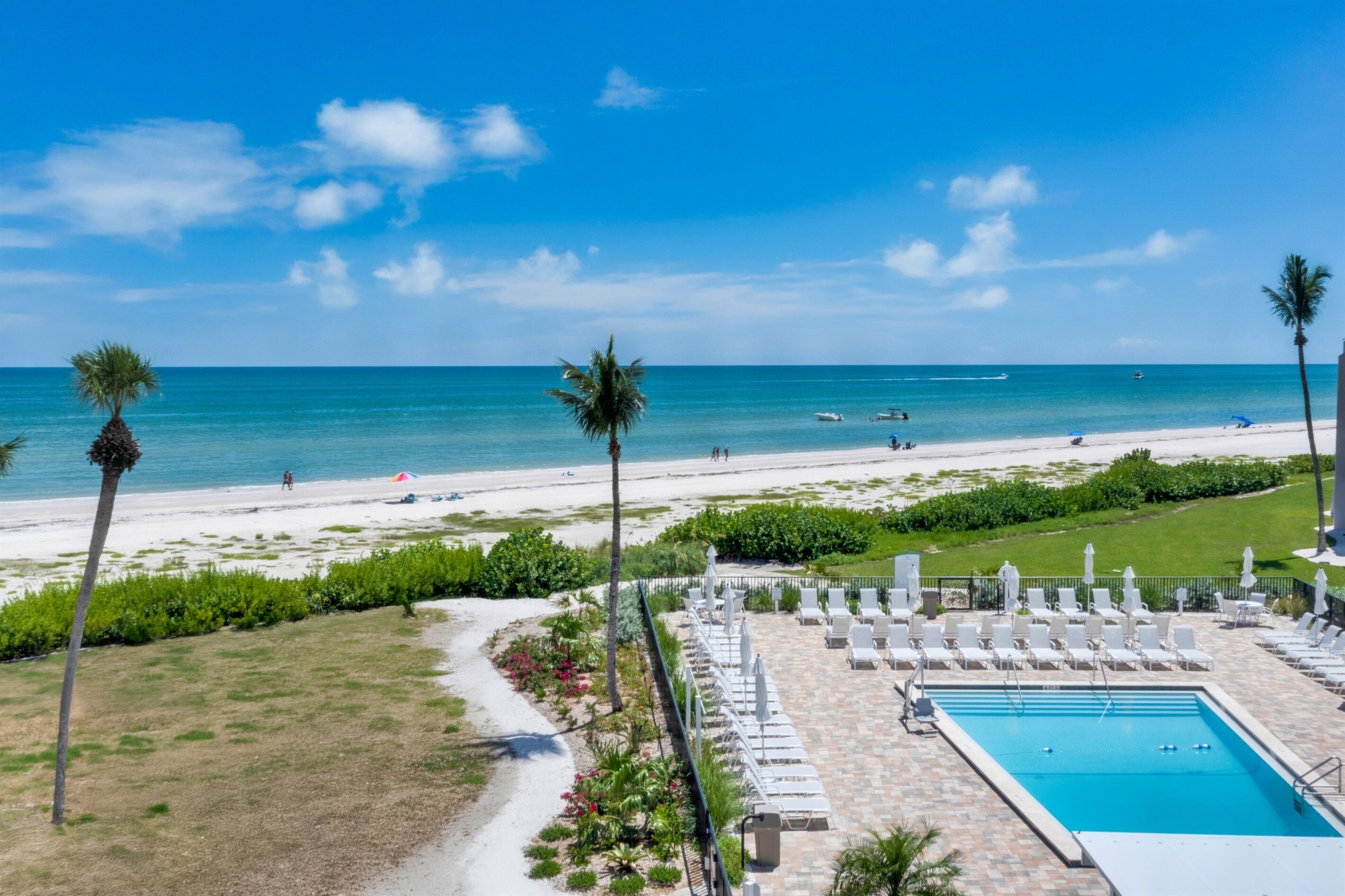A resort with a pool, beach, and palm trees.