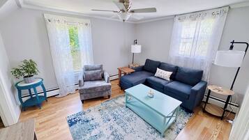 Un salon comprenant un canapé, un fauteuil, une table basse et un ventilateur de plafond.