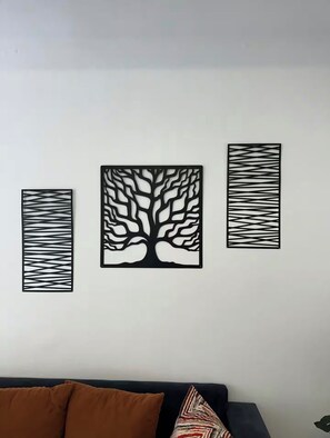 Eine Wand mit drei schwarzen Ziertelementen, davon eines mit einem Baumdekor und zwei mit abstrakten Mustern.