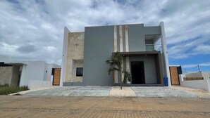 A modern two-story building with a flat roof, a small entrance, and a palm tree in the foreground. - Spacious 4-bedroom townhome in lovely Punta Cana with AC and free WiFi (Punta Cana)