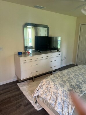 A bedroom with a bed, a dresser, a television, and a mirror. - Relaxing Port LaBelle Retreat / Spacious Home Near Nature & Golf (Port LaBelle)